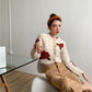 Gilet crème à motifs roses, col rond, boutons visibles