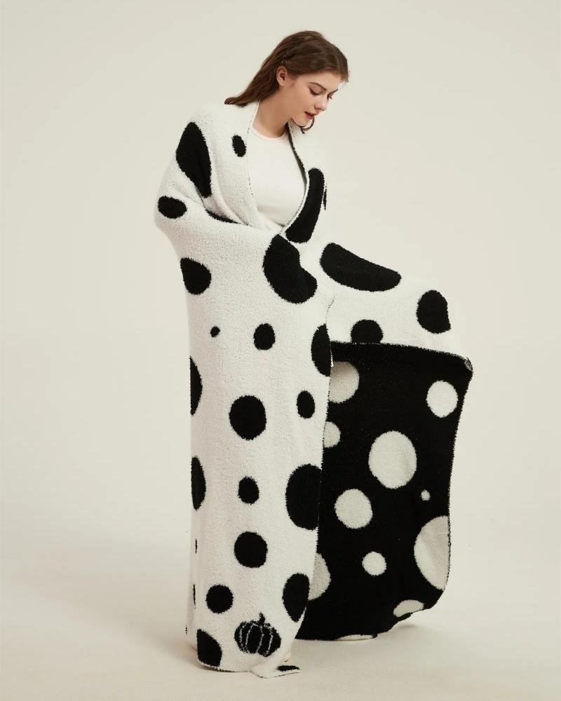 Plaid polaire réversible noir et blanc à pois sur canapé