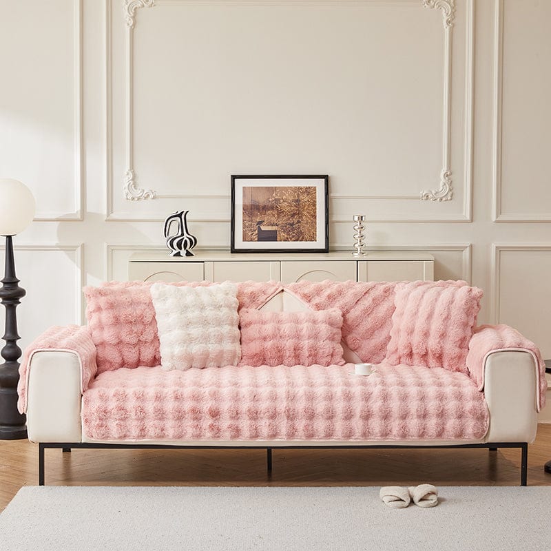 Housse moelleuse rose sur un canapé, prête pour l'hiver