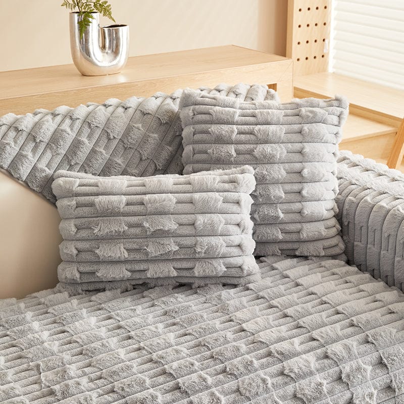 Housse de coussin en fausse fourrure grise sur canapé