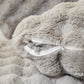 Housse de coussin en fausse fourrure gris clair sur canapé