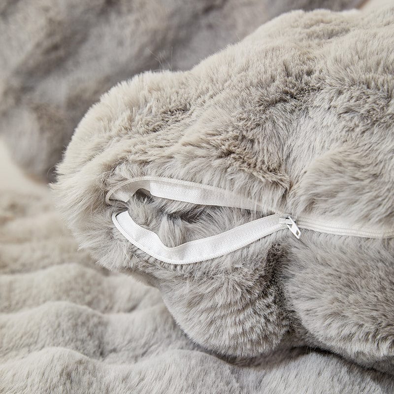 Housse de coussin en fausse fourrure gris clair sur canapé