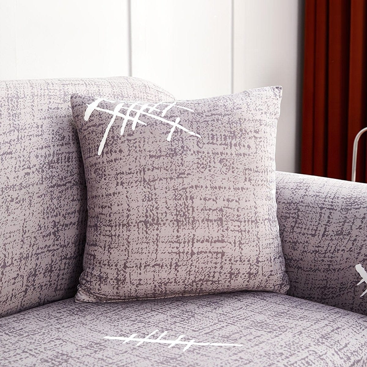 Deux housses de coussin grises extensibles sur un canapé blanc