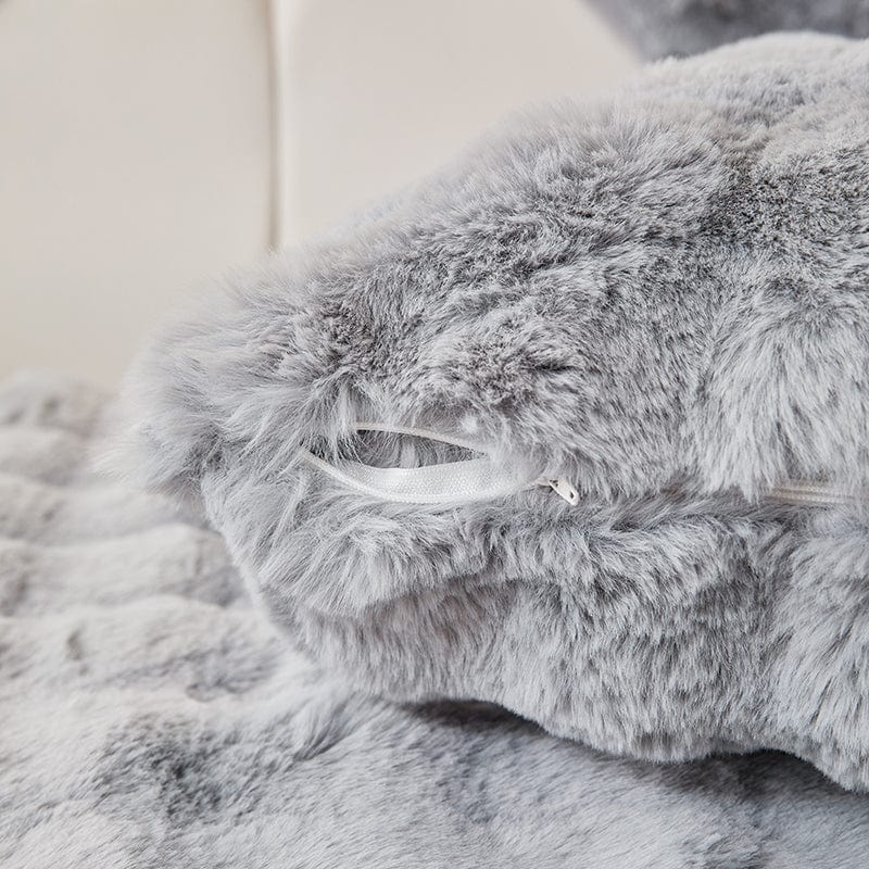 Housse de coussin en fausse fourrure gris perle sur canapé