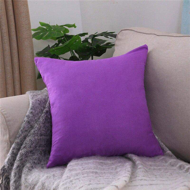 Deux housses de coussin extensibles violettes sur canapé gris