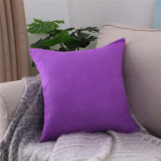 Deux housses de coussin extensibles violettes sur canapé gris