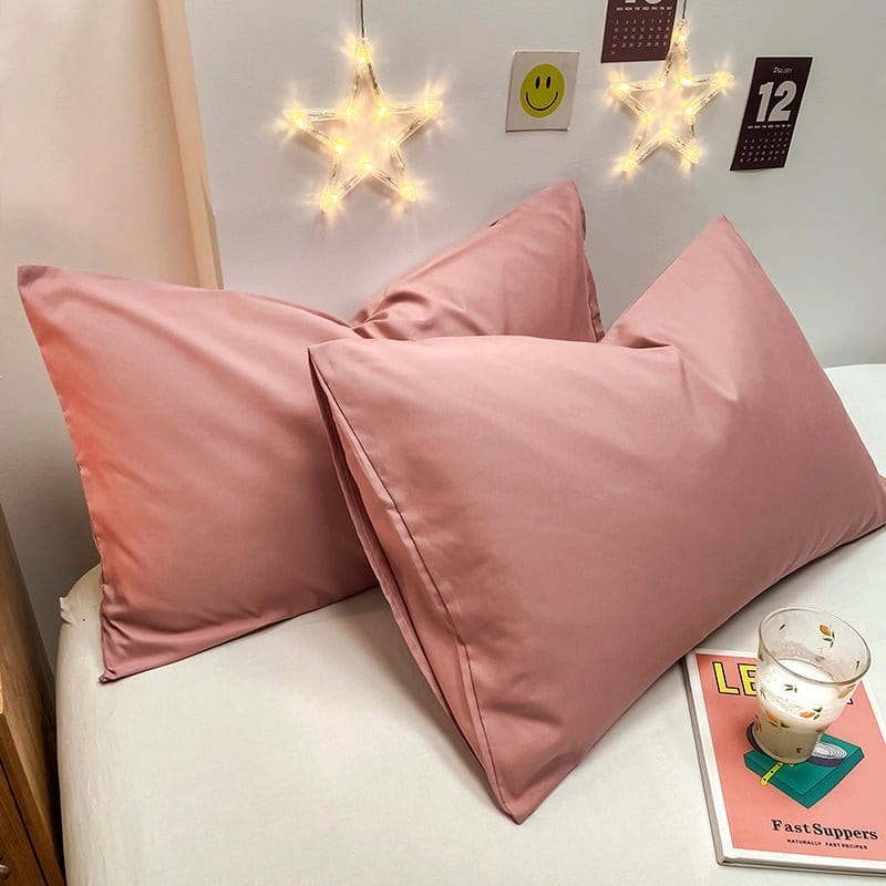 Deux housses de coussin roses sur un canapé gris clair