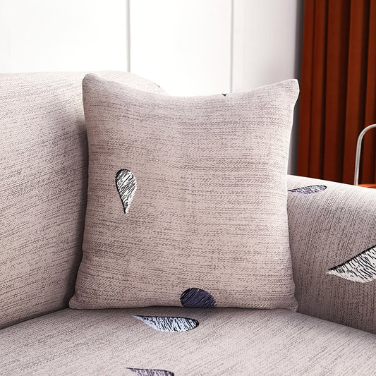 Deux housses de coussin extensibles sur un canapé gris