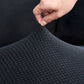 Housse grise sur fauteuil, tissu extensible et ajusté