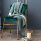 Plaid vert enroulé, posé sur une chaise
