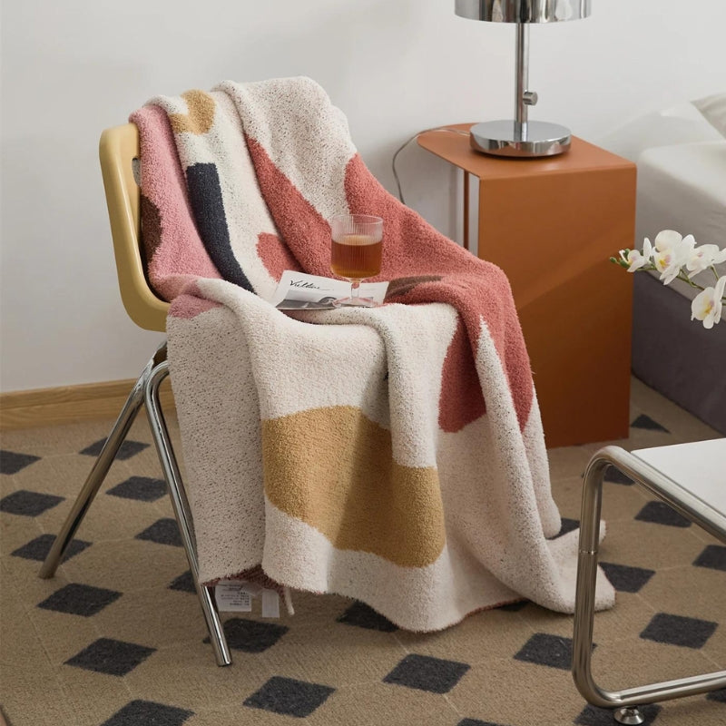 Plaid crème sur canapé, motifs floraux rouges et roses