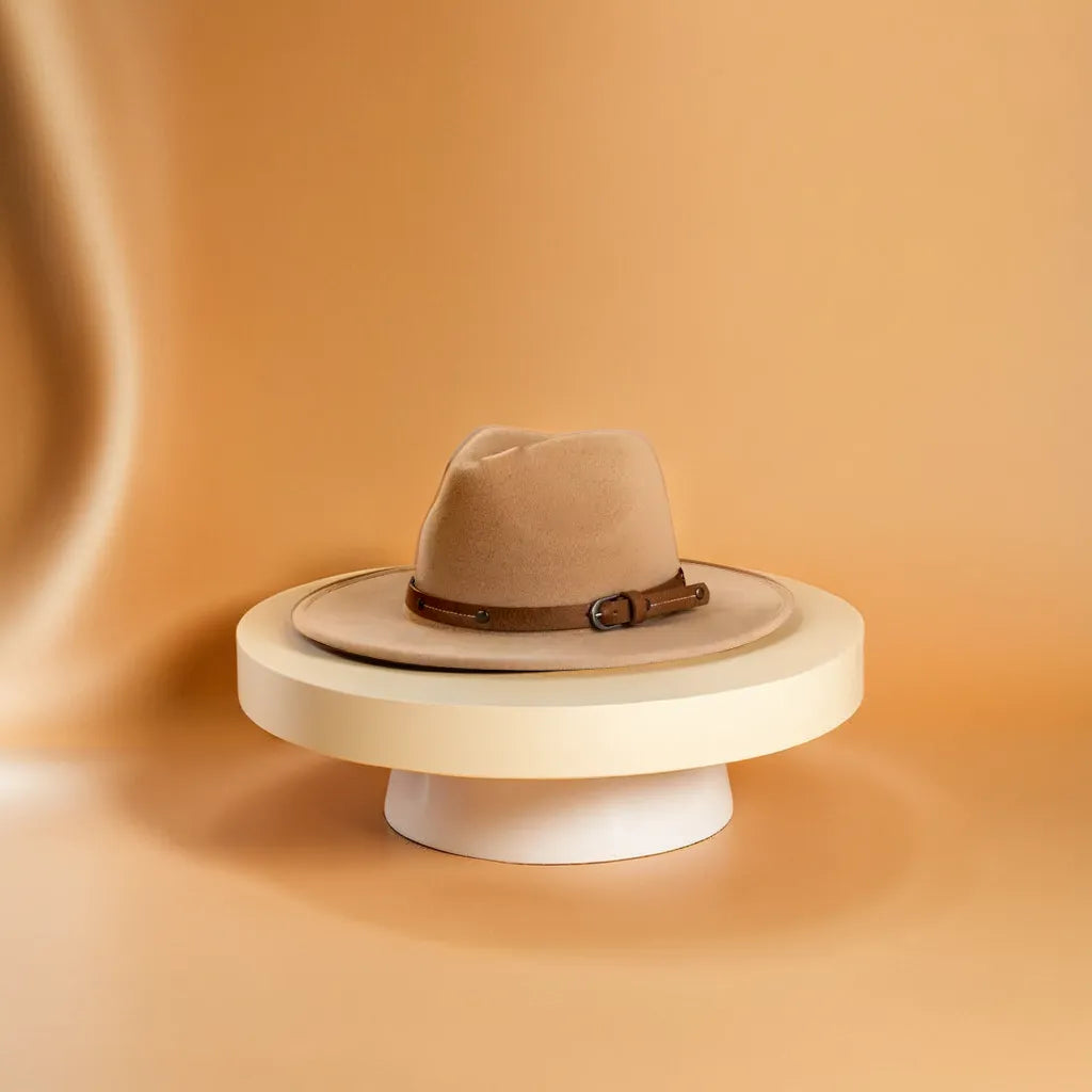 Chapeau Fedora en laine suspendu à un crochet, éclairé par une lumière douce