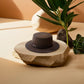 Chapeau Fedora beige posé sur une table en bois
