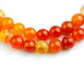Détail des perles d'onyx marbre orange du mala