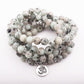 Mala en pierres mouchetées avec pompon blanc