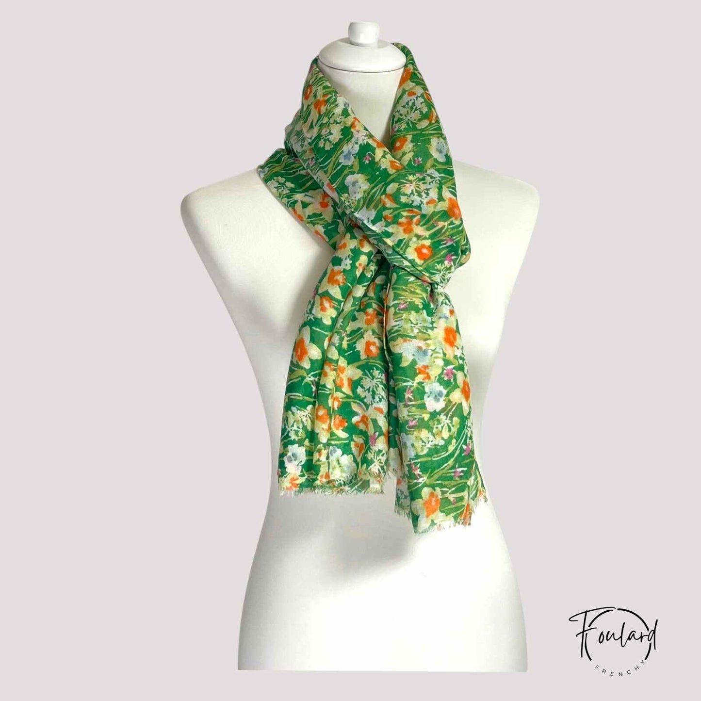 Foulard vert floral enroulé, mettant en valeur sa légèreté