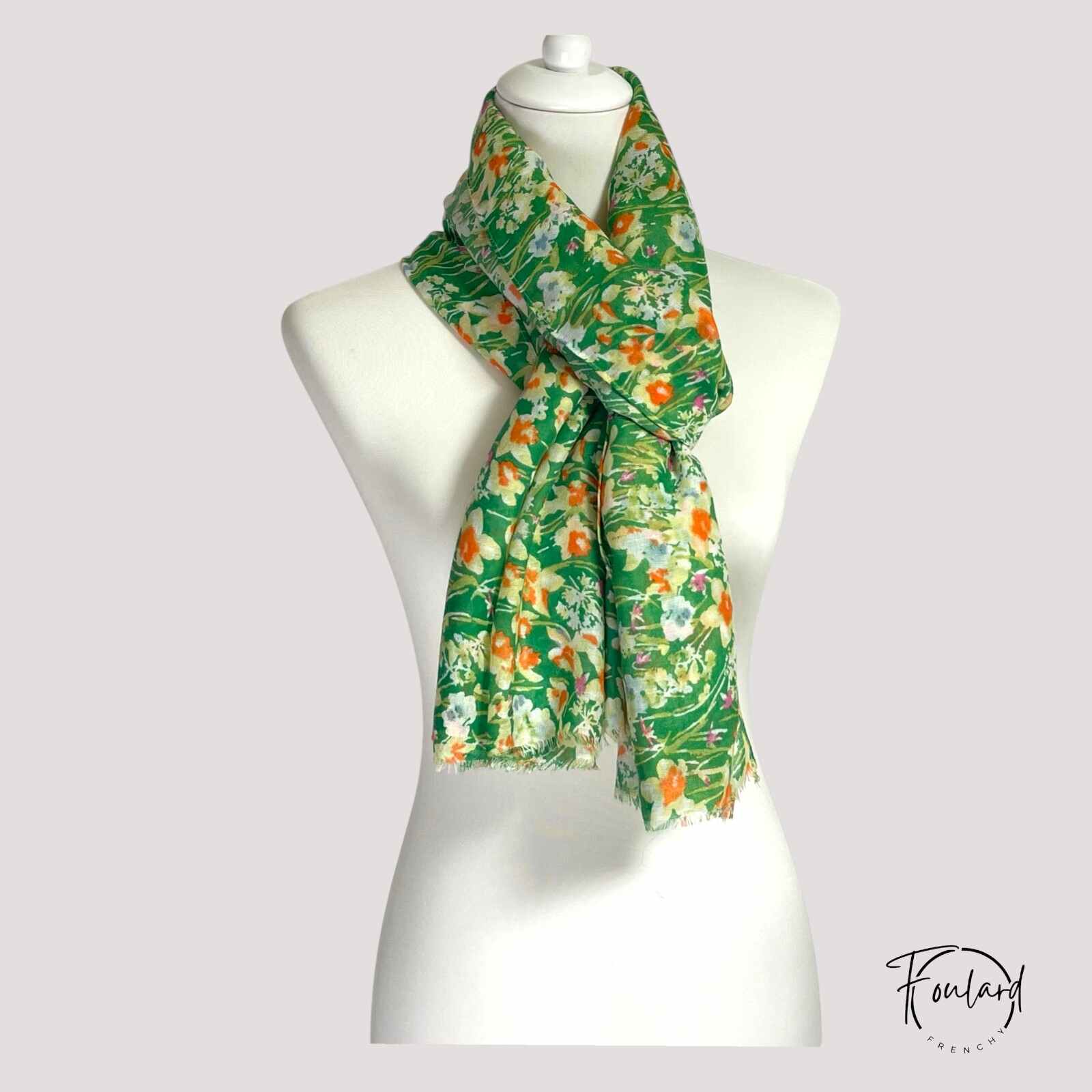 Foulard vert floral enroulé, mettant en valeur sa légèreté