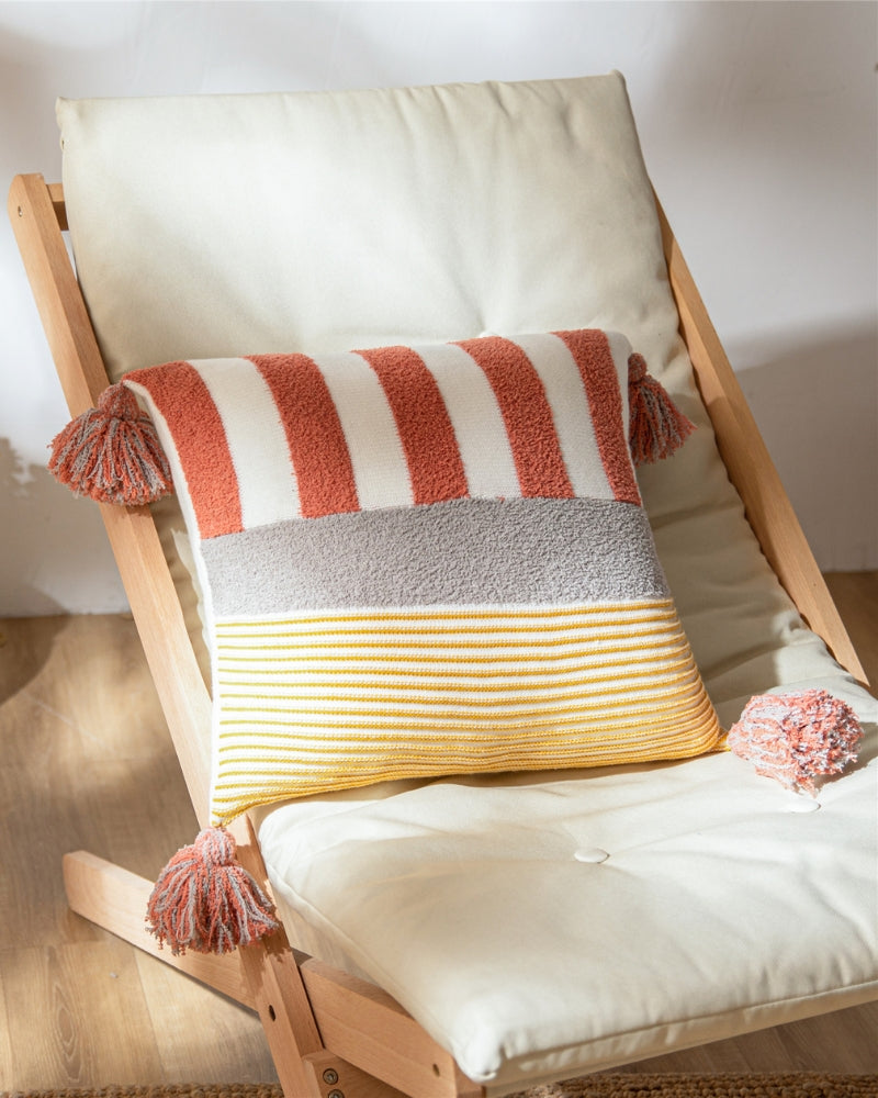 Oreiller marinière en duvet posé sur une chaise, pompons aux coins