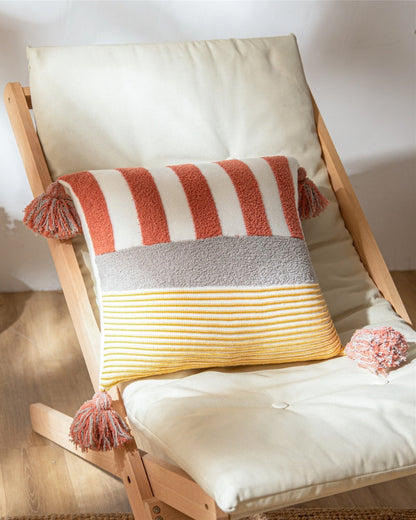 Oreiller marinière en duvet posé sur une chaise, pompons aux coins