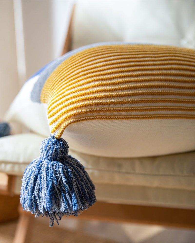 Oreiller marinière en duvet sur un canapé, pompons visibles