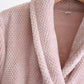Peignoir doux rose posé sur un lit blanc