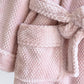 Peignoir rose suspendu à un crochet dans une salle de bain