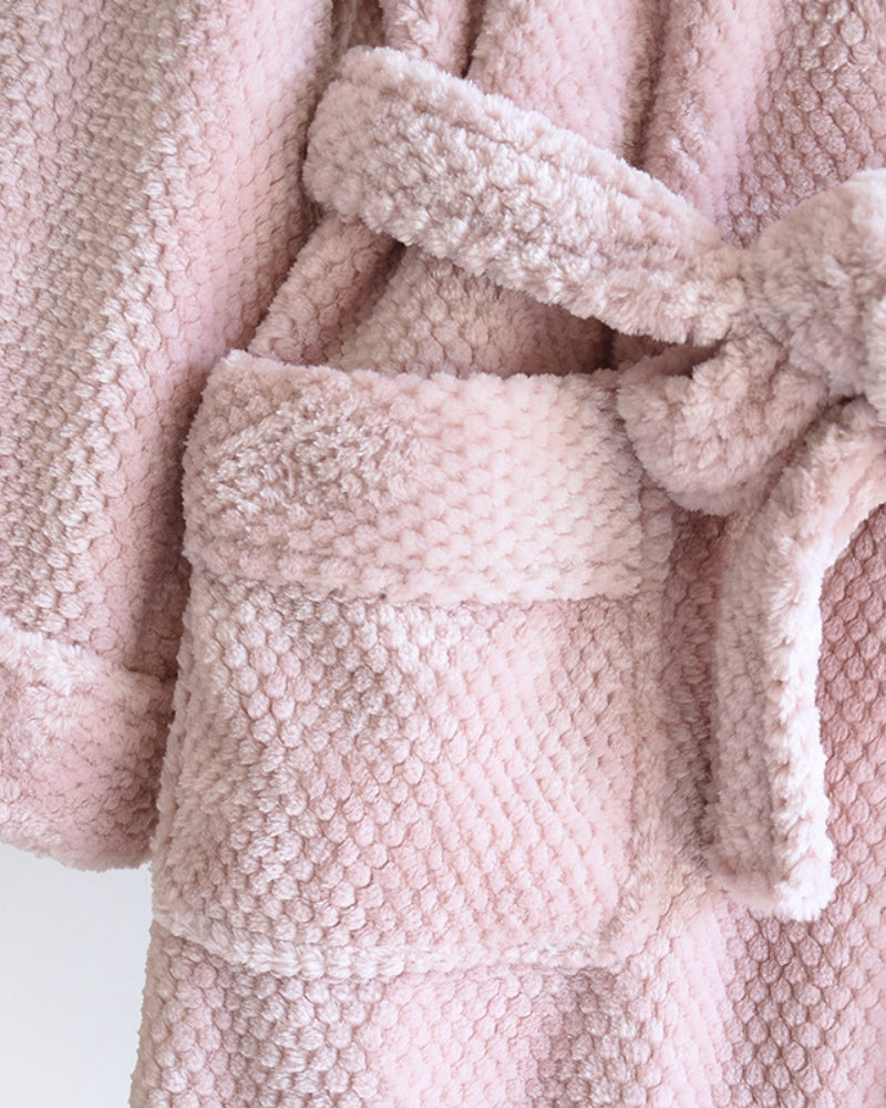 Peignoir rose suspendu à un crochet dans une salle de bain