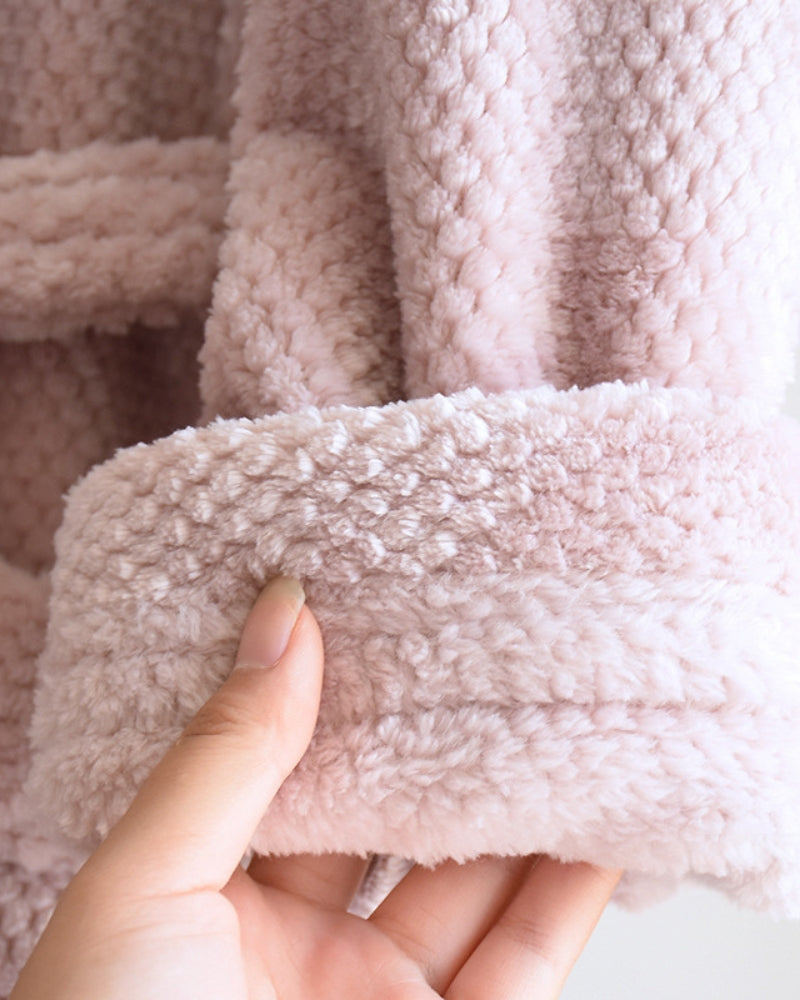 Peignoir rose plié sur une étagère en bois