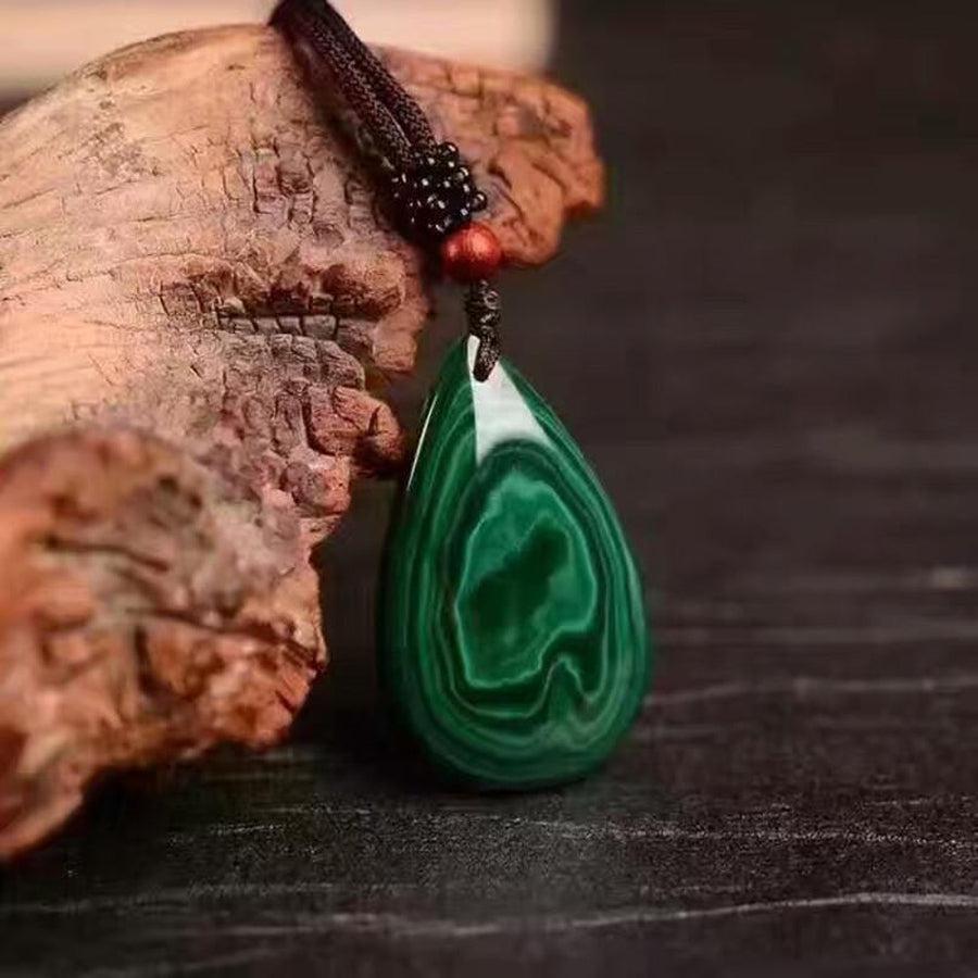Pendentif malachite posé sur une surface en bois clair