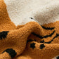 Détail du motif chat orange sur le plaid beige