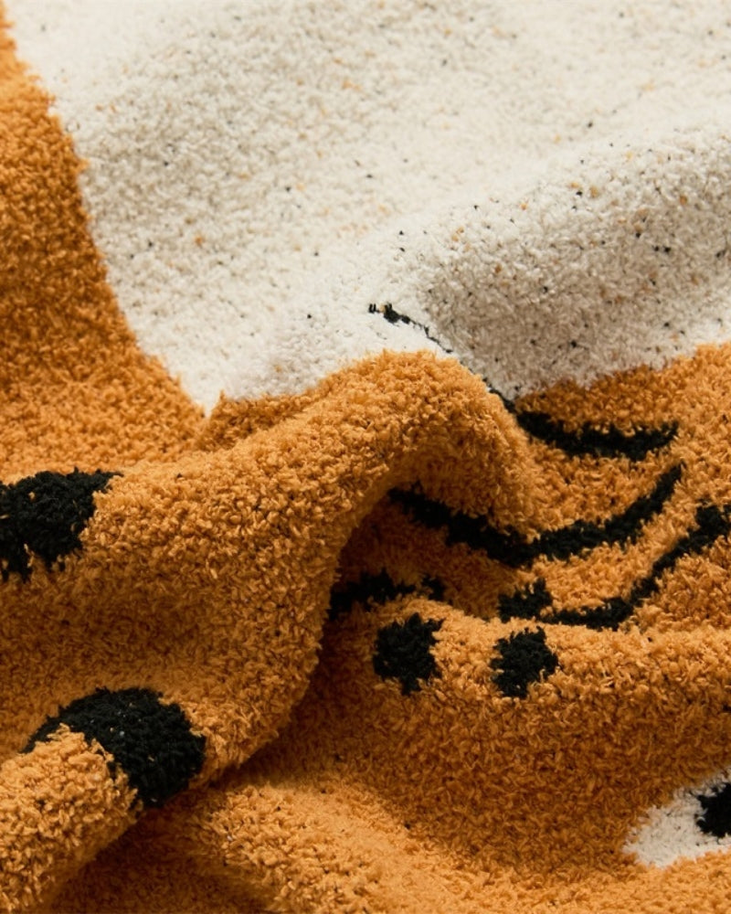 Détail du motif chat orange sur le plaid beige