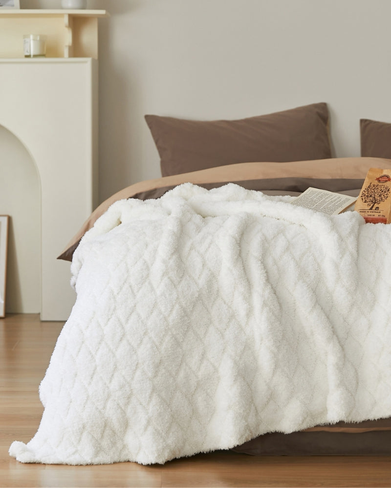 Plaid blanc doux drapé sur un canapé gris
