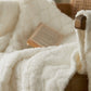 Plaid blanc plié sur un lit, ambiance cocooning