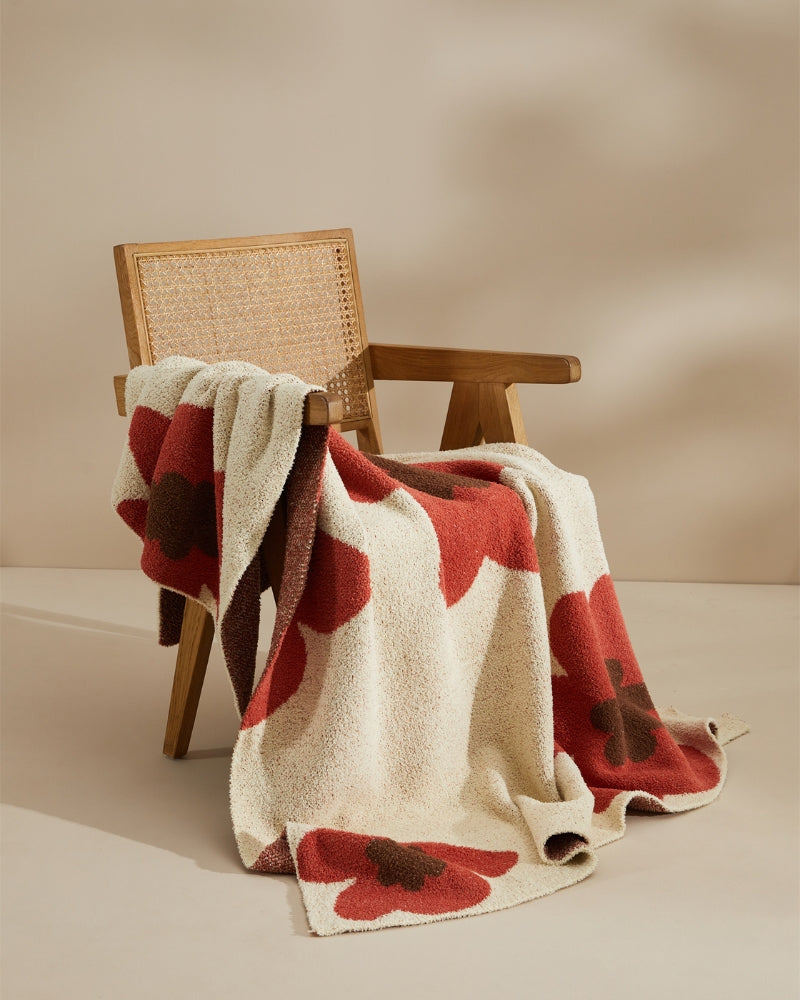 Plaid crème avec motifs de roses rouges sur un canapé