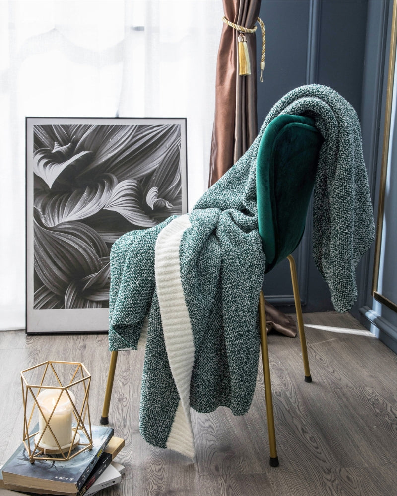 Plaid vert surpiqué, posé sur un canapé gris