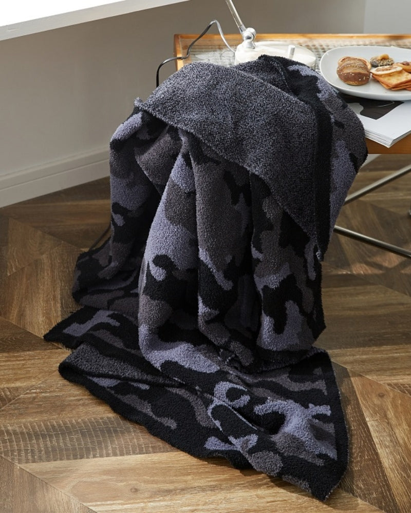 Plaid noir en fausse fourrure étalé sur un lit