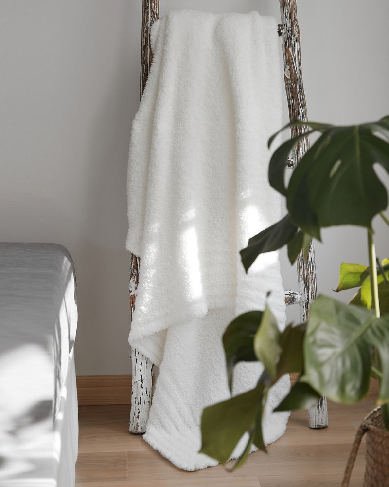 Plaid blanc en fourrure sur un canapé gris