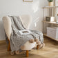 Ambiance cosy avec plaid gris sur canapé clair