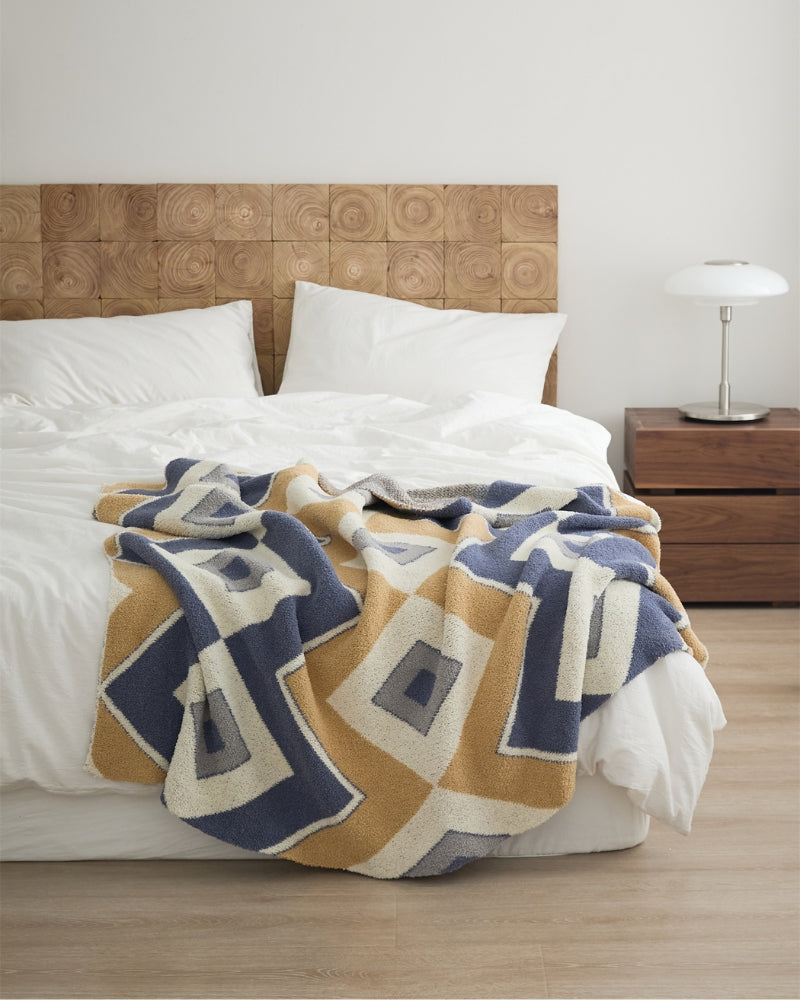 Plaid polaire avec motifs croisés sur canapé beige