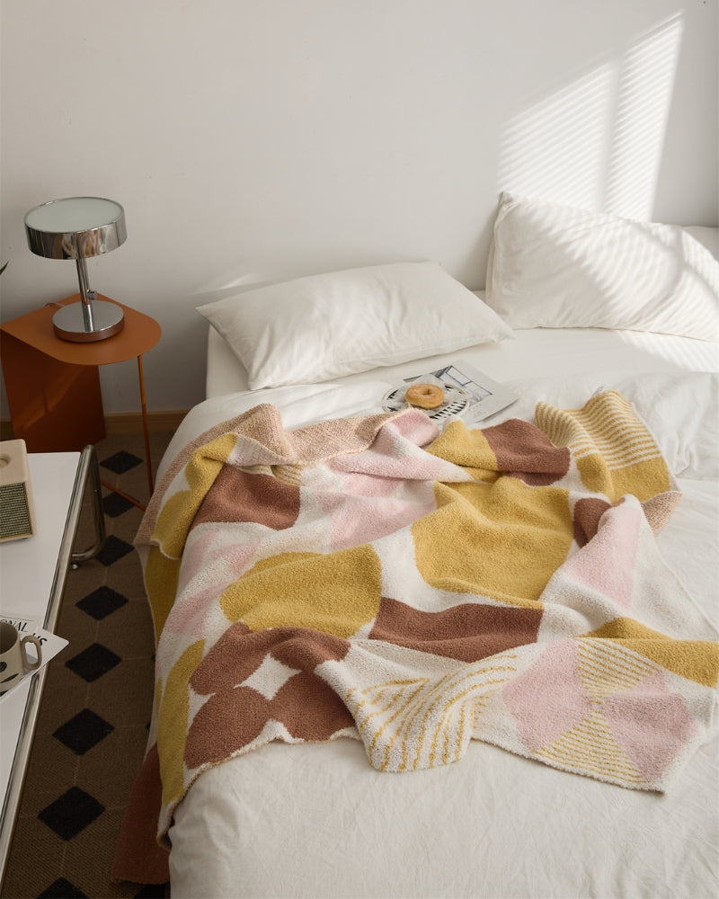 Plaid en sherpa avec motifs géométriques colorés sur canapé