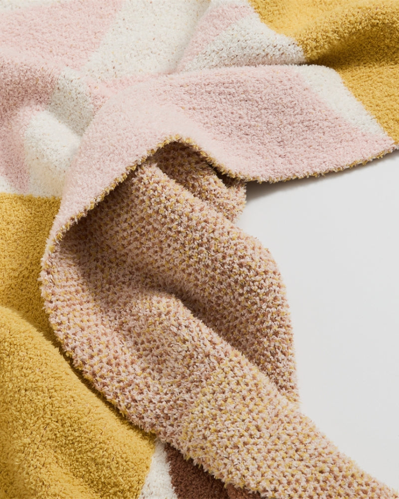 Plaid bohème drapé sur un fauteuil, motifs marron visibles