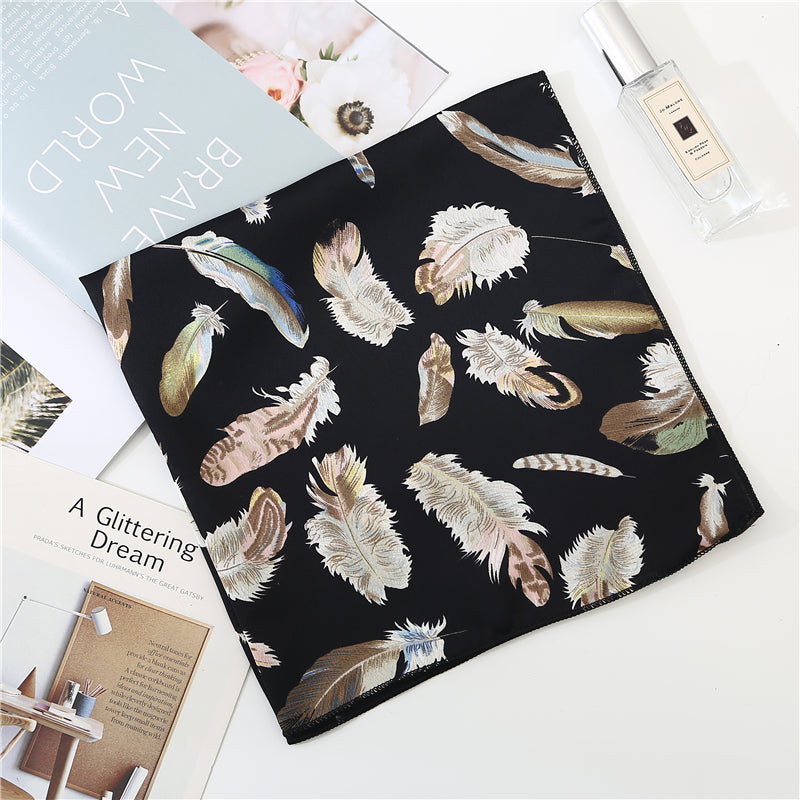 Gros plan sur les motifs plumes du foulard noir