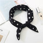 Gros plan sur le tissu noir à pois du foulard