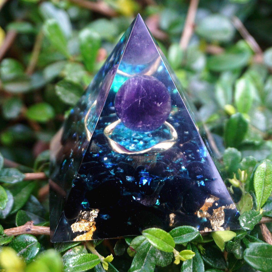 Pyramide orgonite posée sur une surface en bois clair