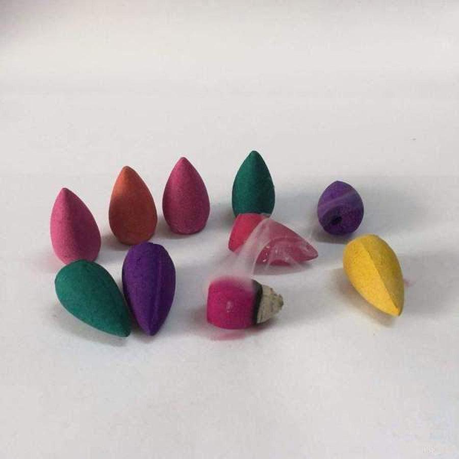 Cônes d'encens colorés disposés en éventail sur une surface blanche