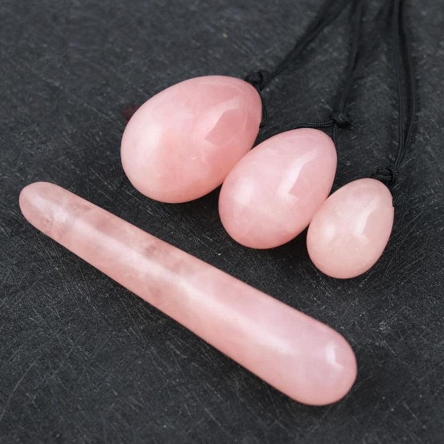 Trois œufs de Yoni en quartz rose alignés sur fond blanc