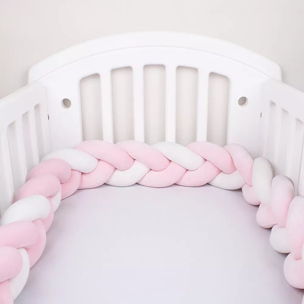Tour de lit tressé rose et blanc sur lit bébé