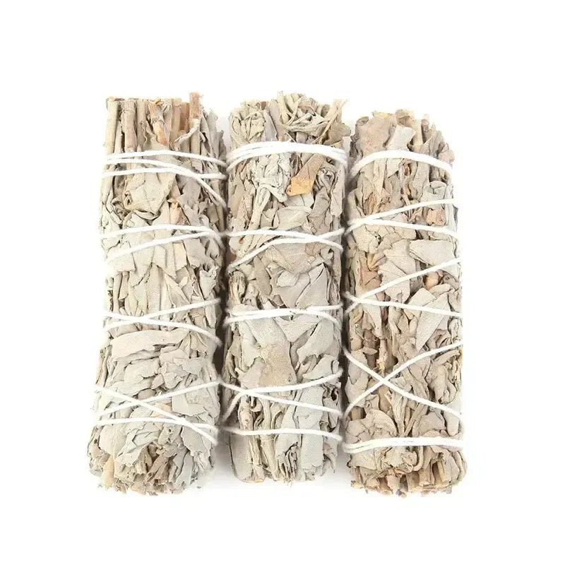 Trio de bâtons de sauge blanche posés sur une surface en bois