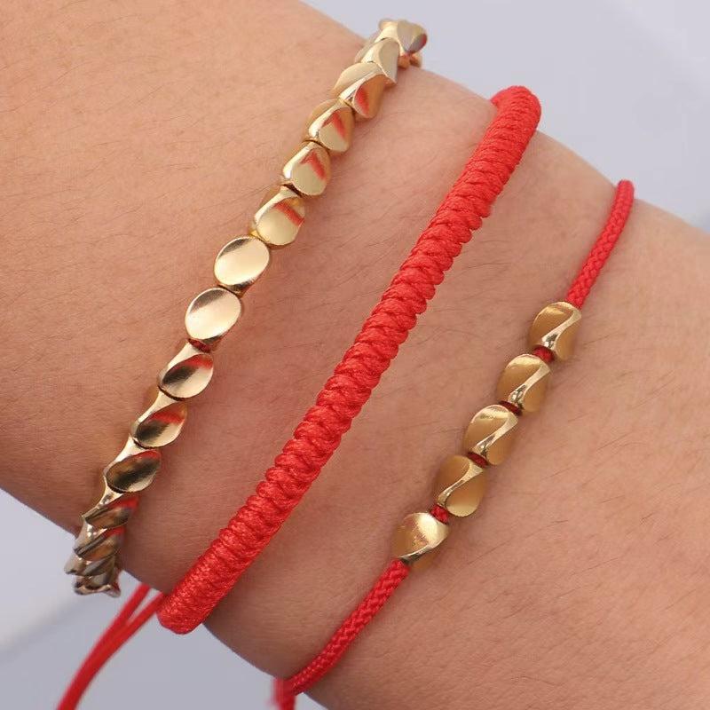 Gros plan sur perles de cuivre et fil rouge tressé
