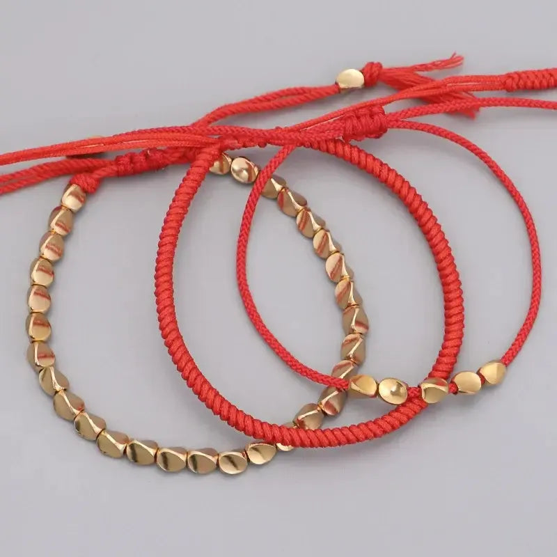 Vue détaillée des perles de cuivre sur bracelet rouge